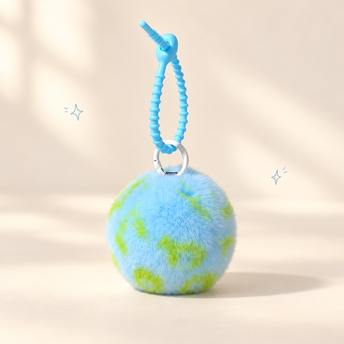 Earth Plush Keychain on a softly lit cream and pastel background.