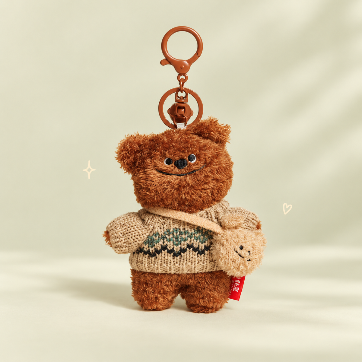 Sweater Bear Plush keychain on a softly lit cream and pastel background.