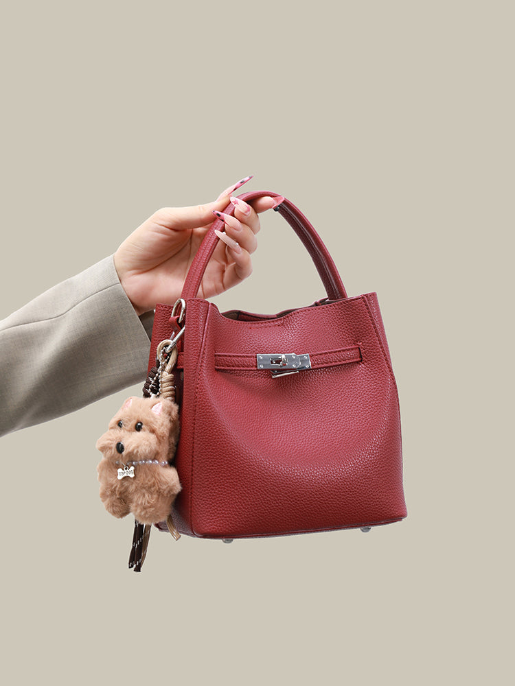 Wine red mini bucket bag held by the top handle with plush dog charm
