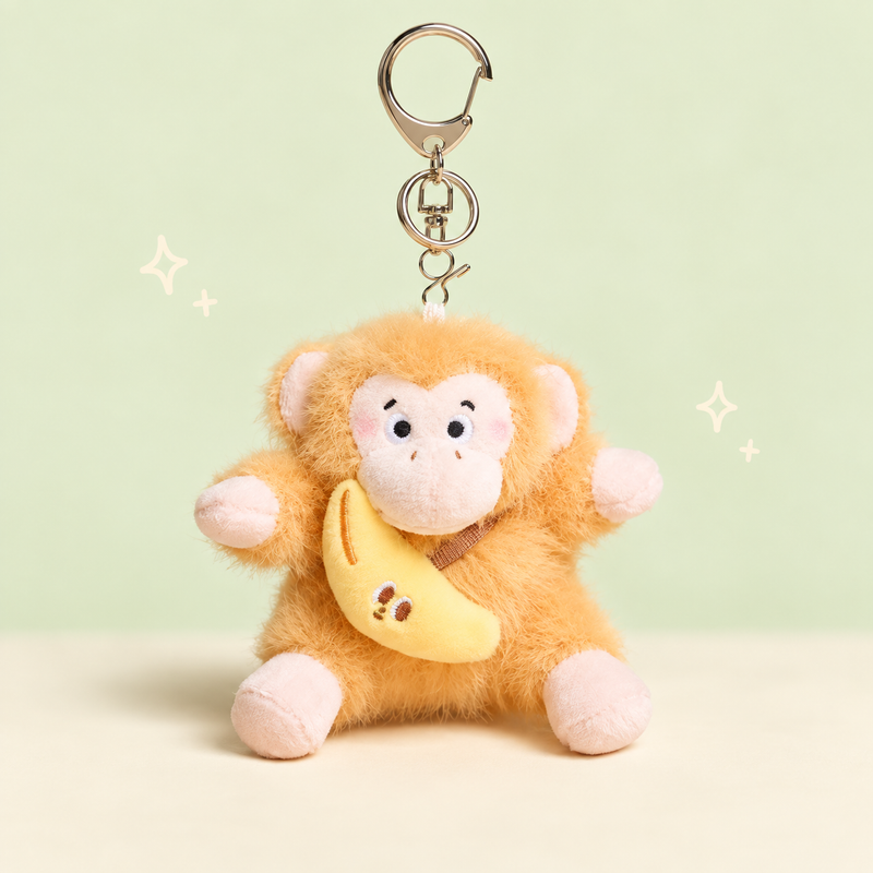 Banana Monkey Plush Charm on a softly lit cream and pastel background.