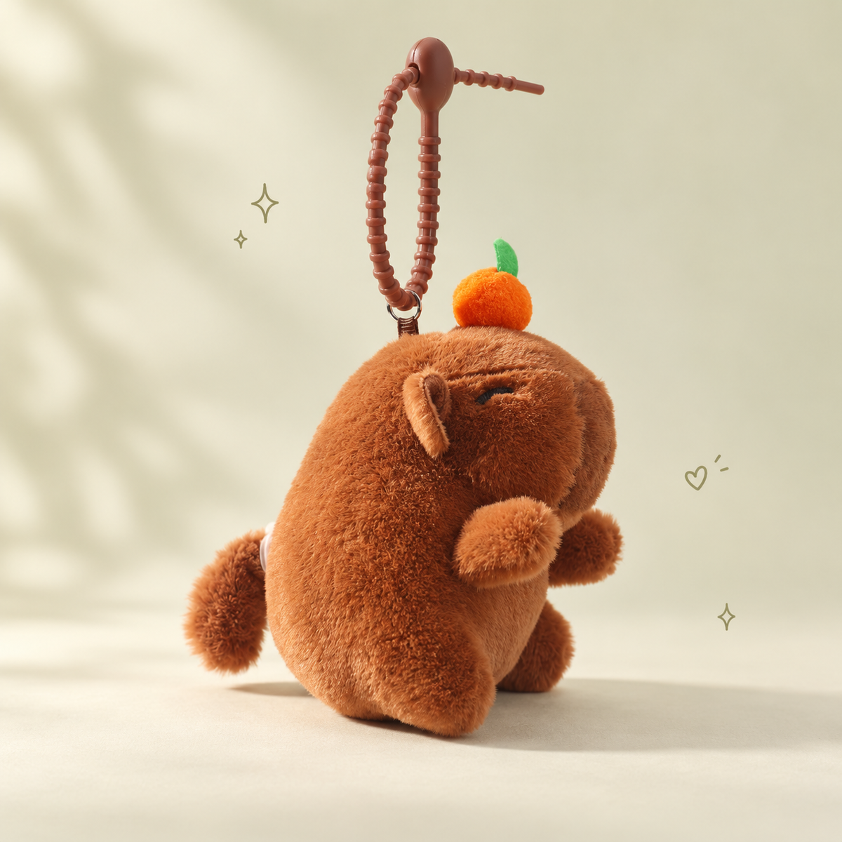Capybara Plush Keychain on a softly lit cream and pastel background.