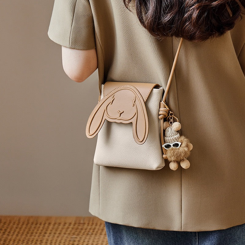Khaki rabbit mini bag worn crossbody with a neutral jacket