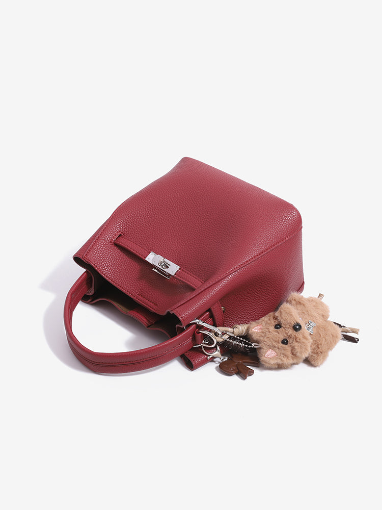 Wine red mini bucket bag lying on its side with dog charm and silver-tone turn lock